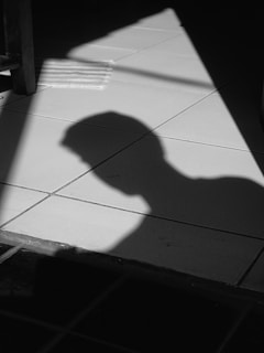 shadow of person on white floor tiles