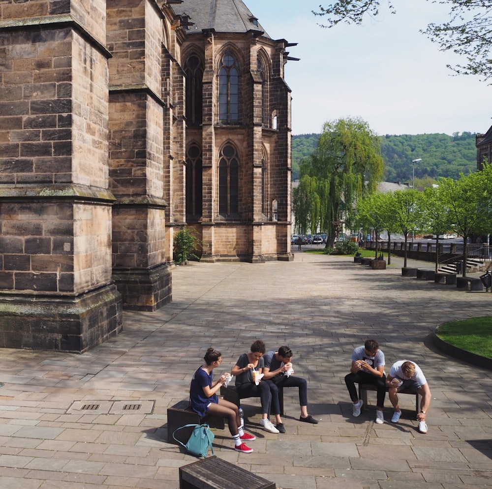 people sitting on bench near brown concrete building during daytime