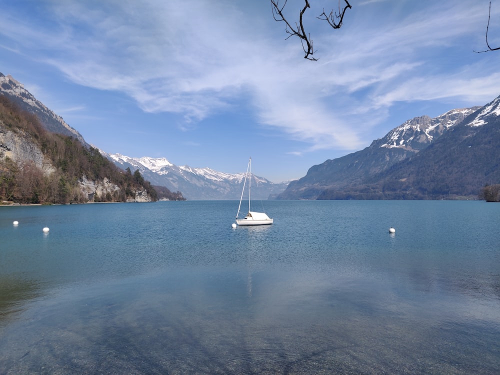 white sailboat on sea near mountain under blue sky during daytime