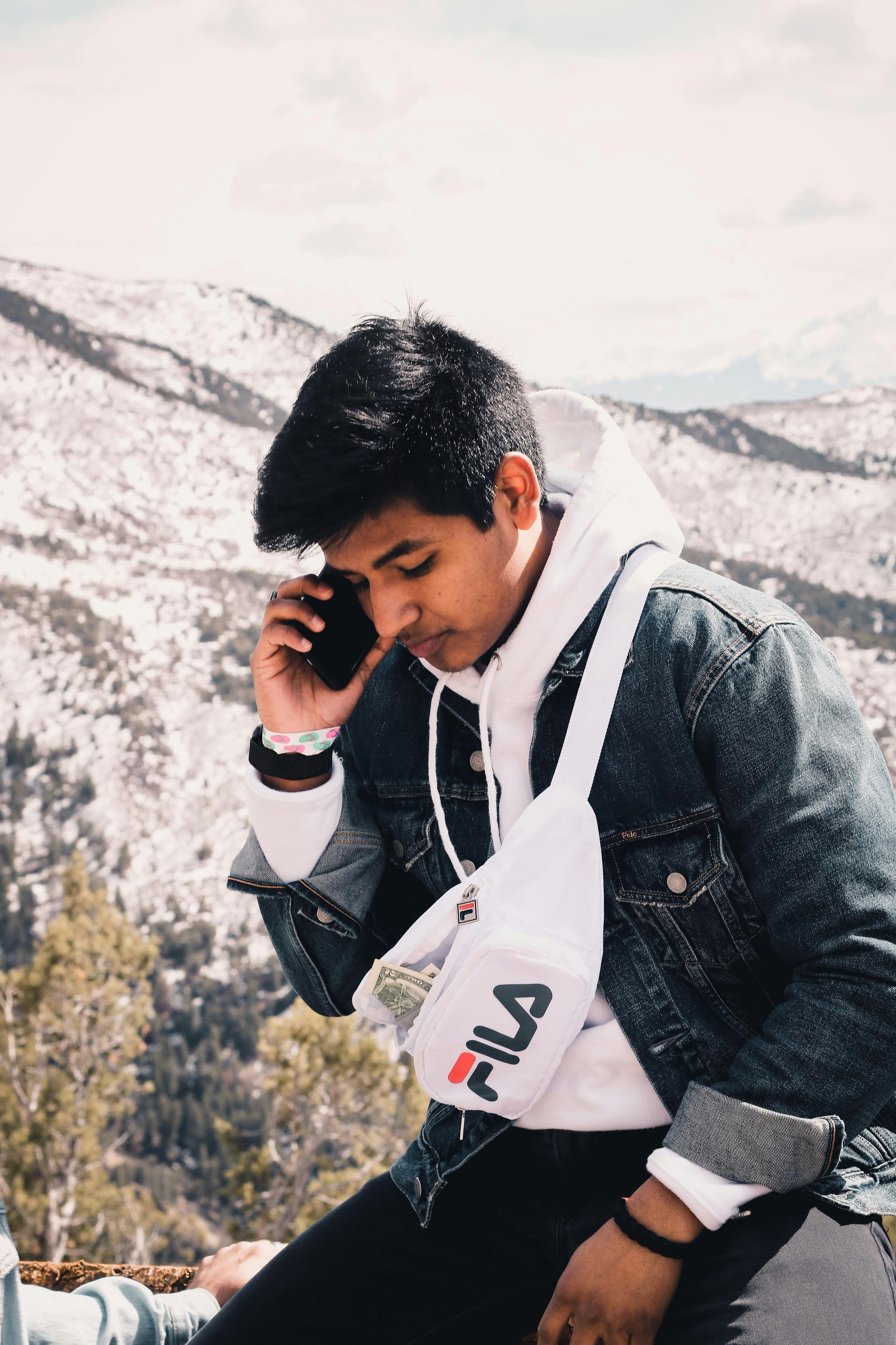 Pria dengan jaket denim hitam memegang smartphone