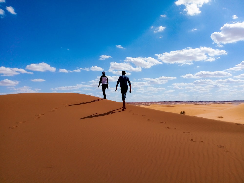 Mann und Frau gehen tagsüber unter blauem Himmel in der Wüste spazieren