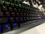 Close-up of a gamer’s hands on a colorful mechanical keyboard with RGB lighting