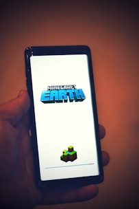a hand holding a cell phone with a game on the screen