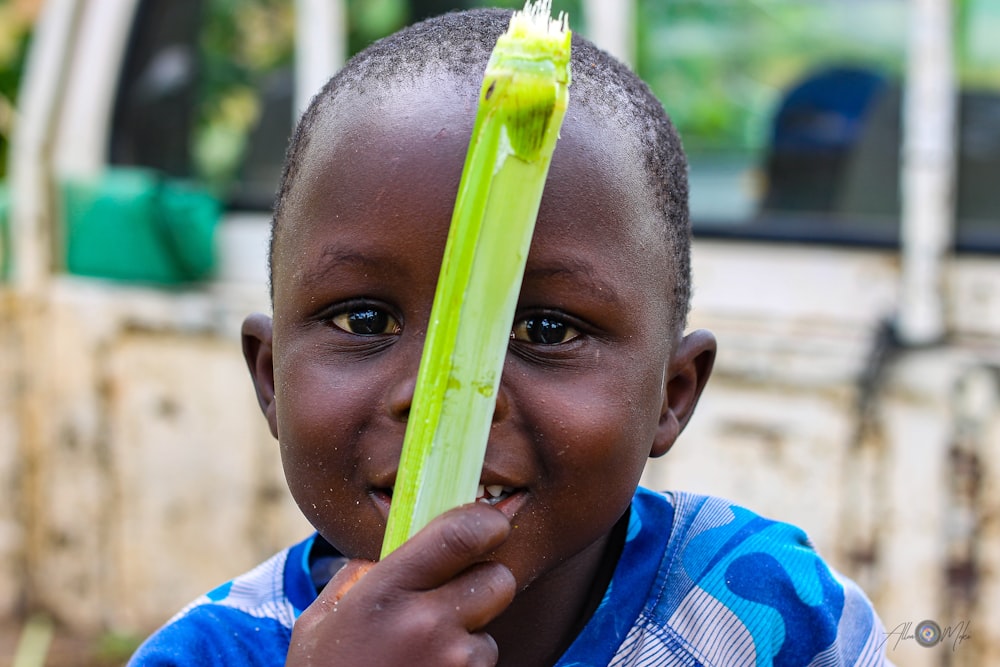 boy in blue and white stripe shirt holding green plastic toy