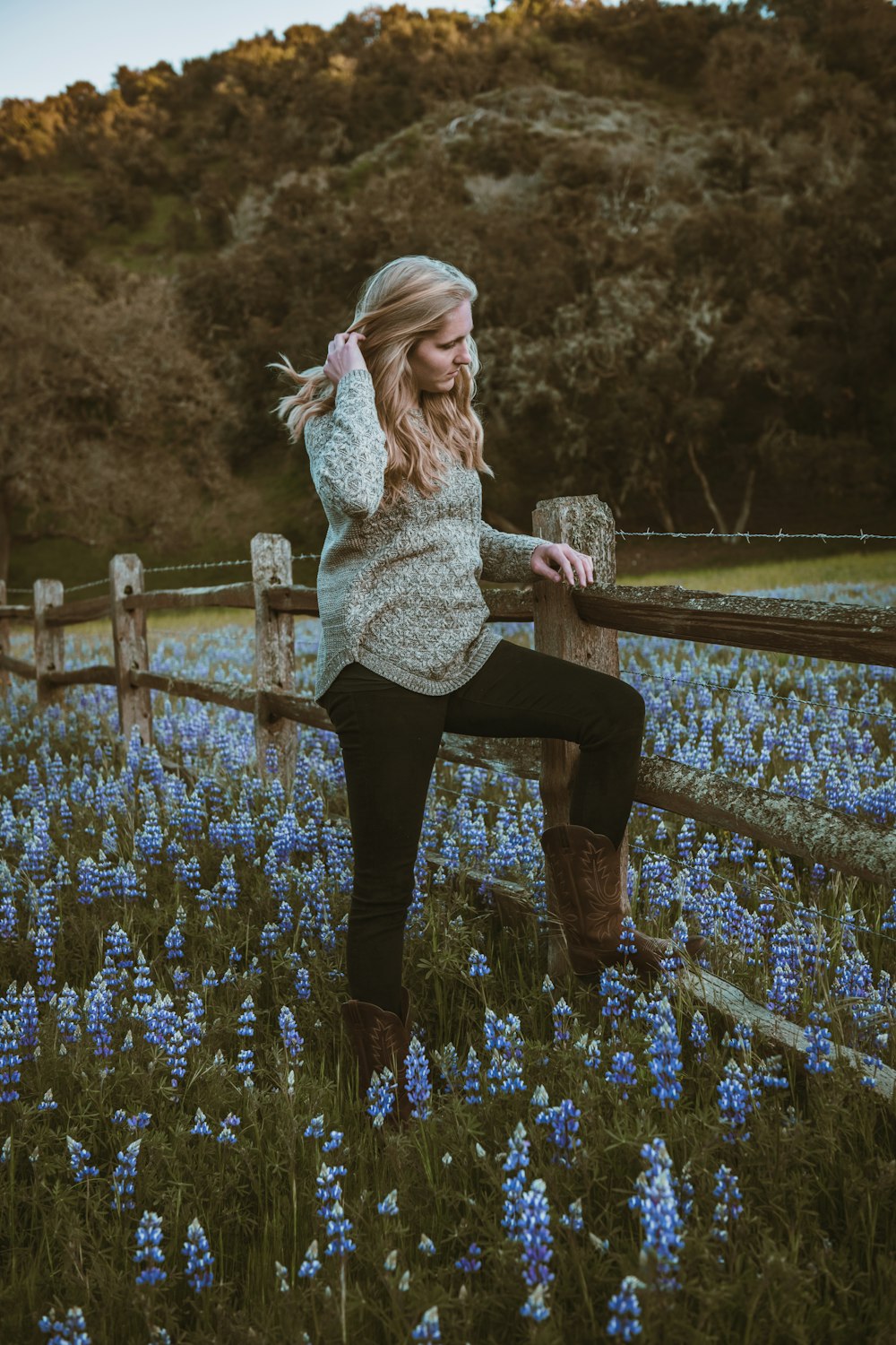 woman in white and black floral long sleeve shirt and black pants standing on purple flower