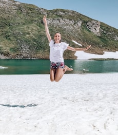 woman in white shirt and blue shorts jumping on water during daytime