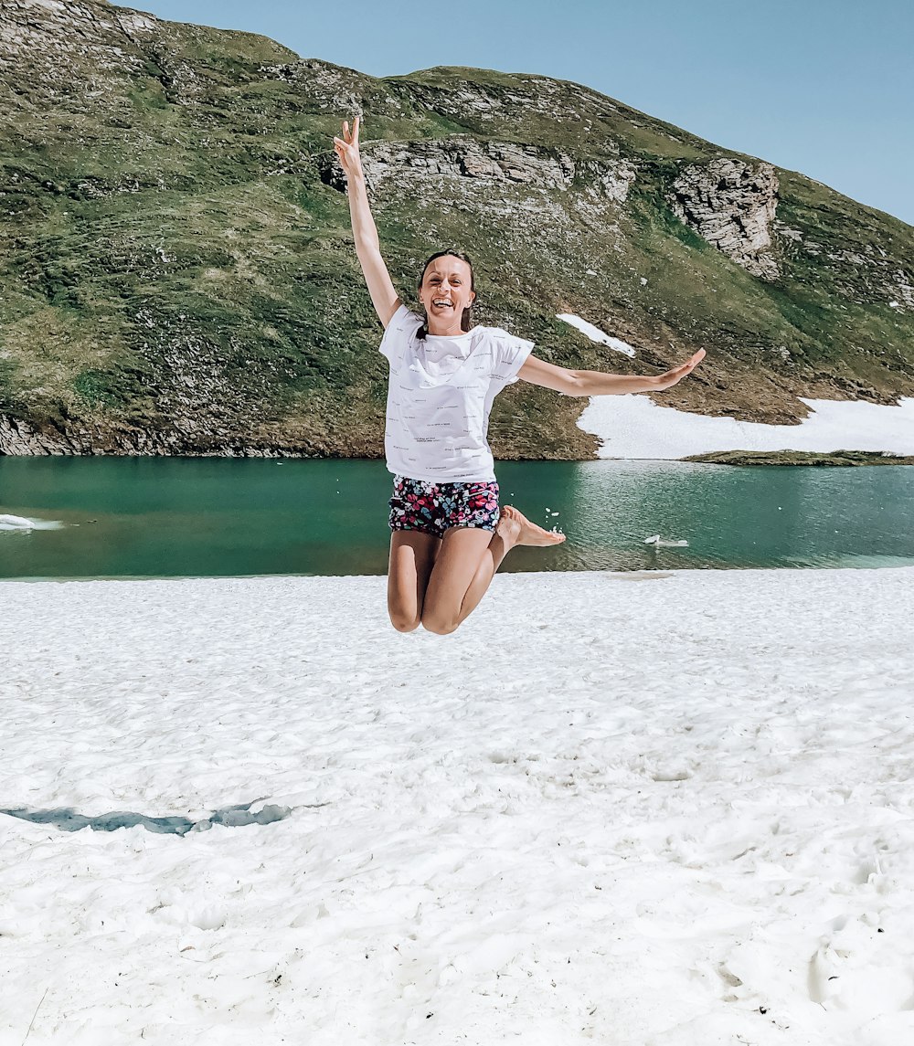 woman in white shirt and blue shorts jumping on water during daytime