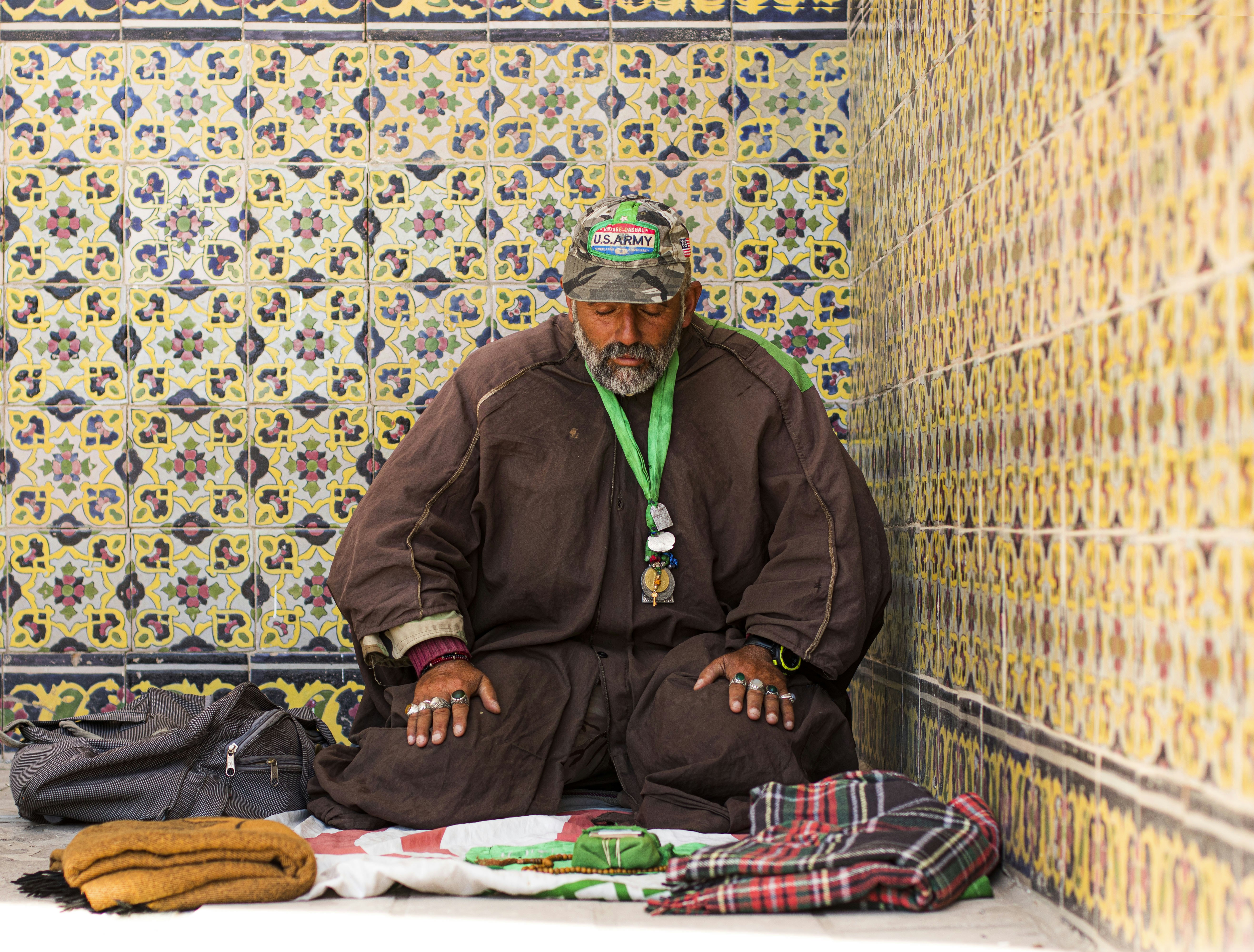 Man in brown jacket sitting on red and white textile