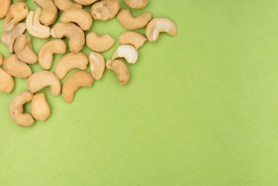 Fresh cashew nuts in a natural burlap sack surrounded by green leaves and sunlight.