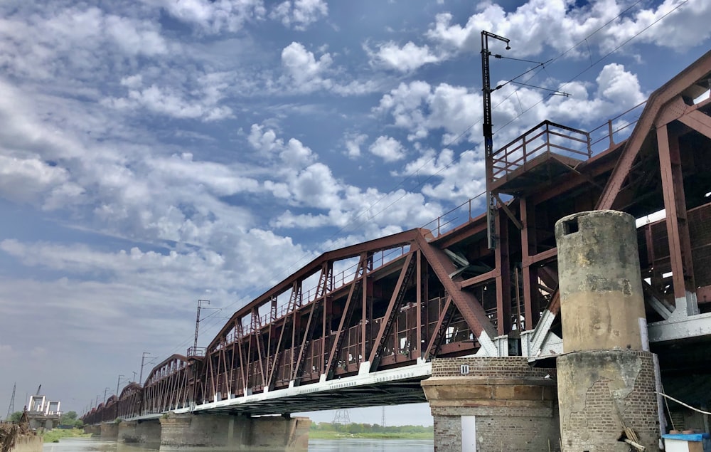 red metal bridge under blue sky and white clouds during daytime