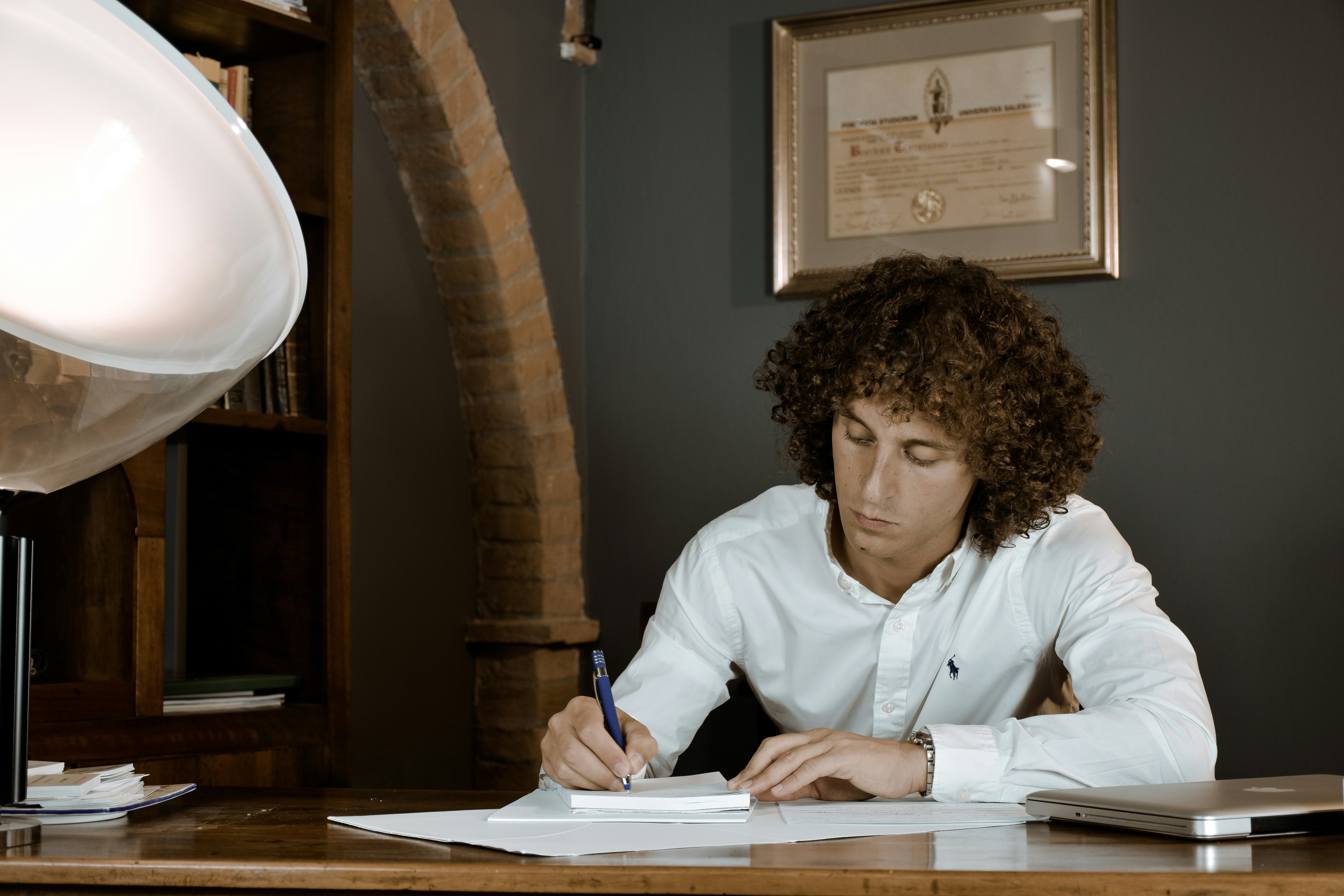 woman in white dress shirt holding pen writing on white paper