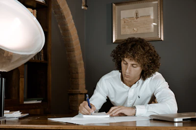 woman in white dress shirt holding pen writing on white paper
