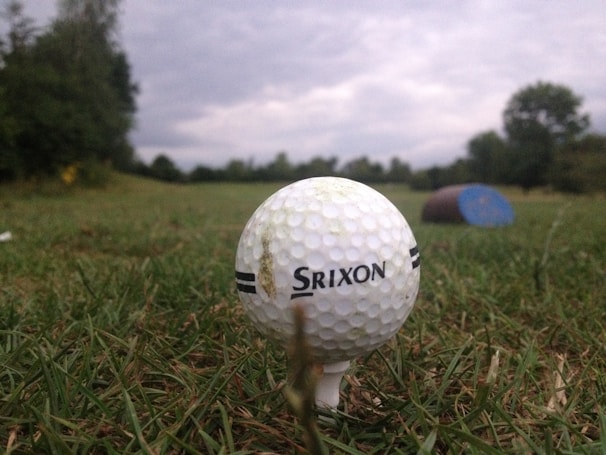 Close-up of a golf ball on a rugged tee against a stormy sky, symbolizing grit and determination.