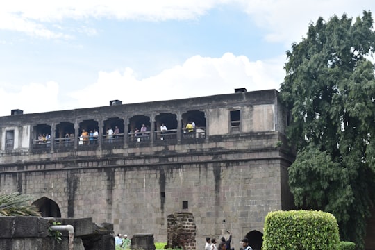 people walking on gray concrete building during daytime in Shaniwar Wada India