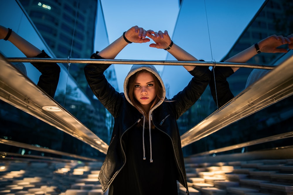 woman in black zip up jacket standing on brown wooden dock during daytime