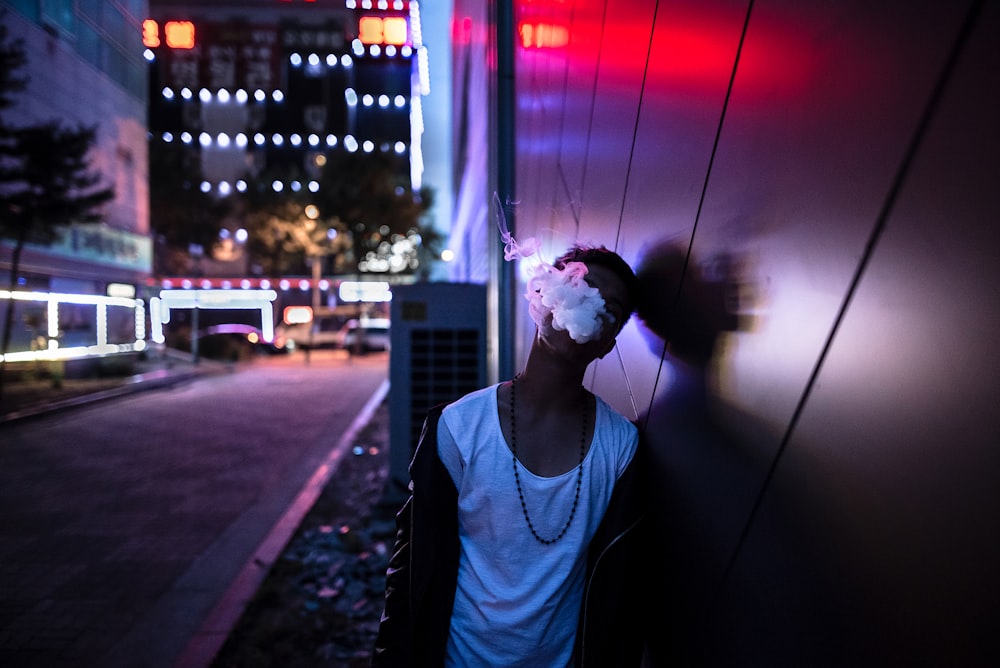 man in blue crew neck shirt standing on street during night time