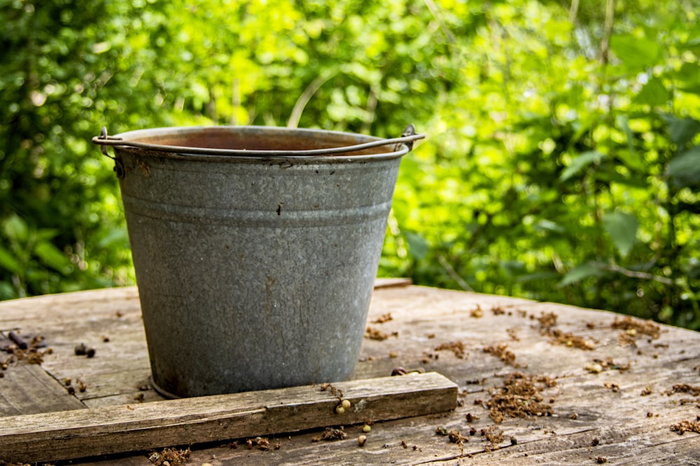 gray steel bucket on brown wooden table