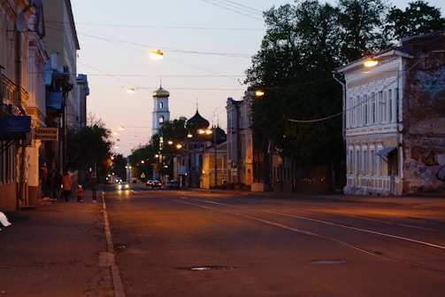 A quiet street at dusk with a single light illuminating a small shrine to Saint Jude