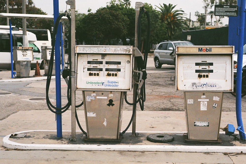 white gas pump near green trees during daytime