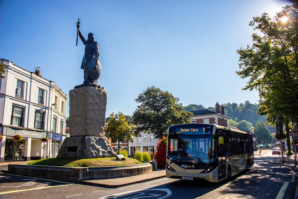 black statue of man riding on horse near brown bus during daytime