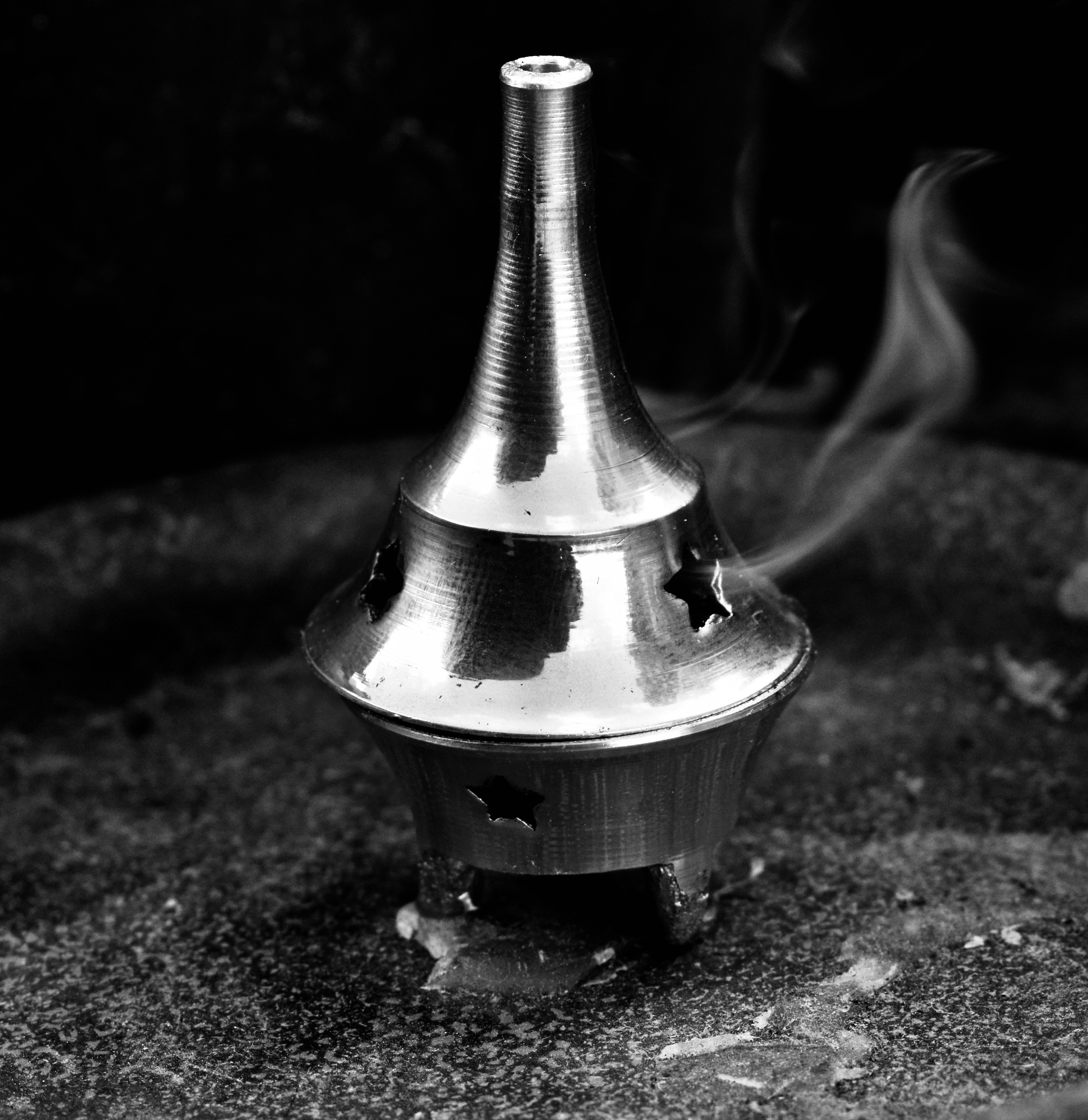 Handcrafted silver incense burner with smoke wisps on dark background