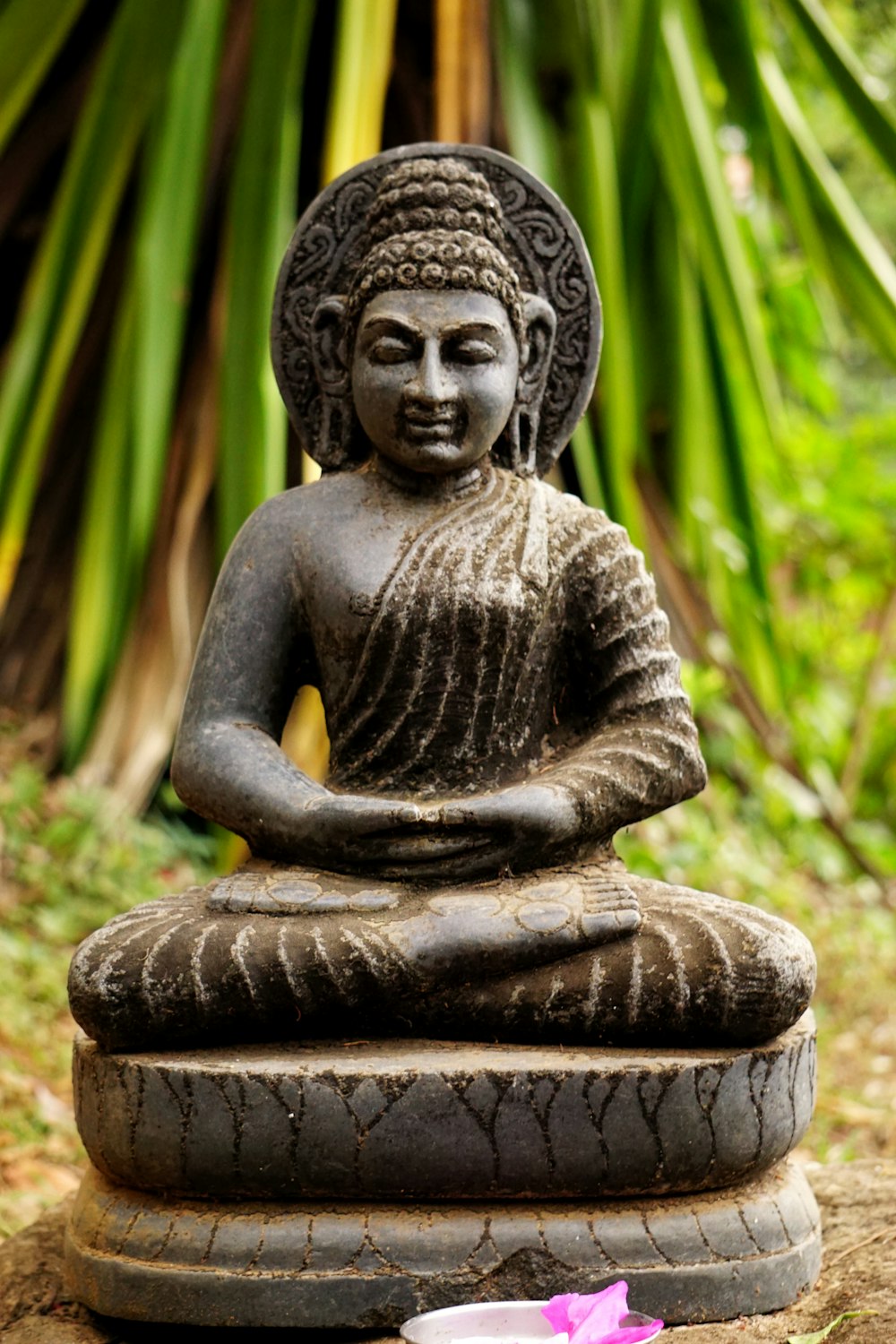 gray concrete buddha statue near green plants during daytime