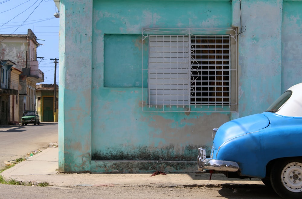 blue and white motor scooter parked beside blue concrete building