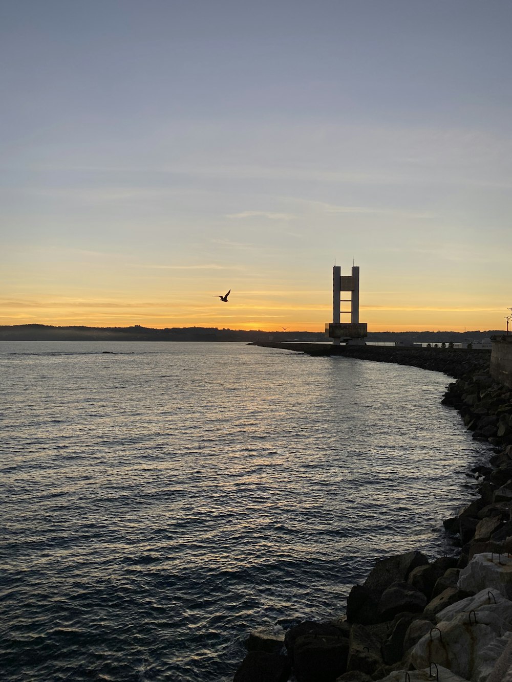 Silhouette des Leuchtturms in der Nähe des Gewässers während des Sonnenuntergangs