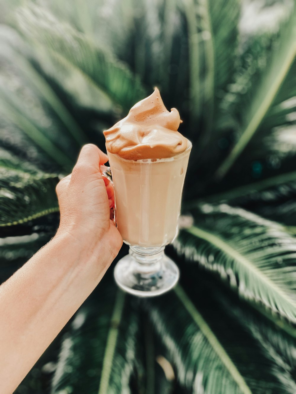 person holding clear glass cup with brown liquid