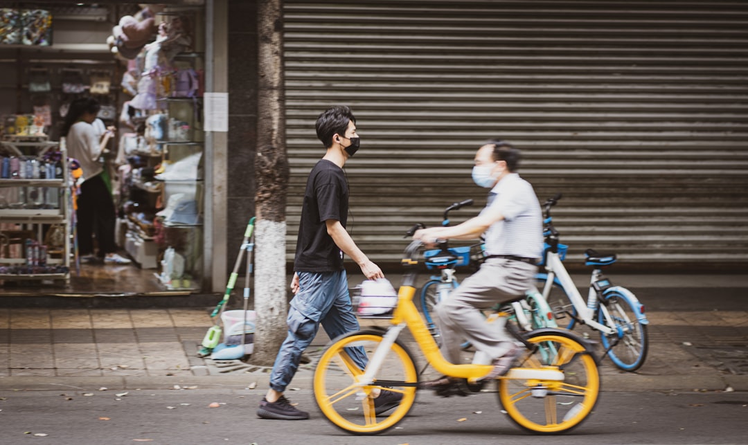 man in black t-shirt and blue denim jeans riding yellow bicycle