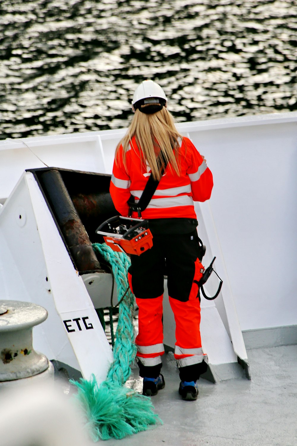 woman in orange jacket and white cap standing on boat during daytime