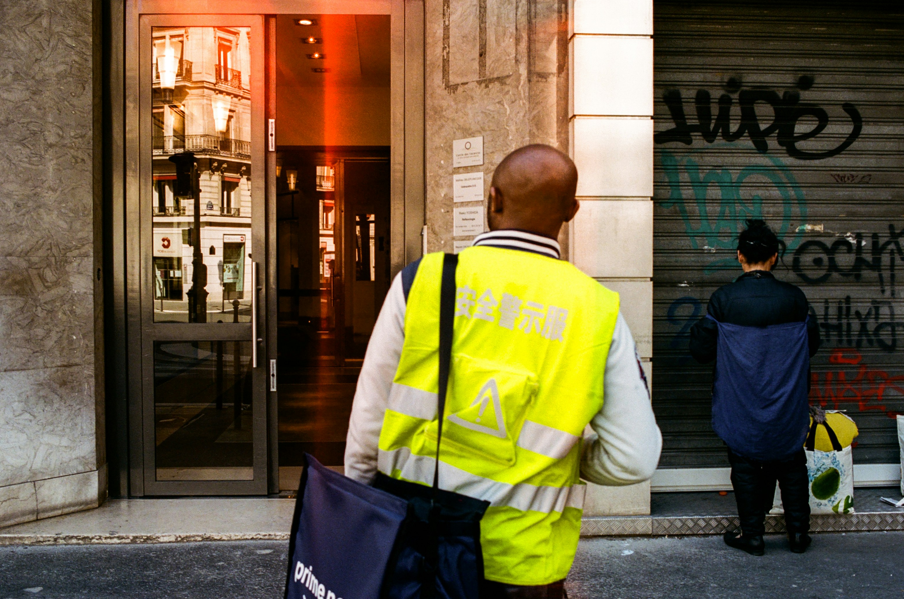 man in yellow and black jacket standing near building during daytime