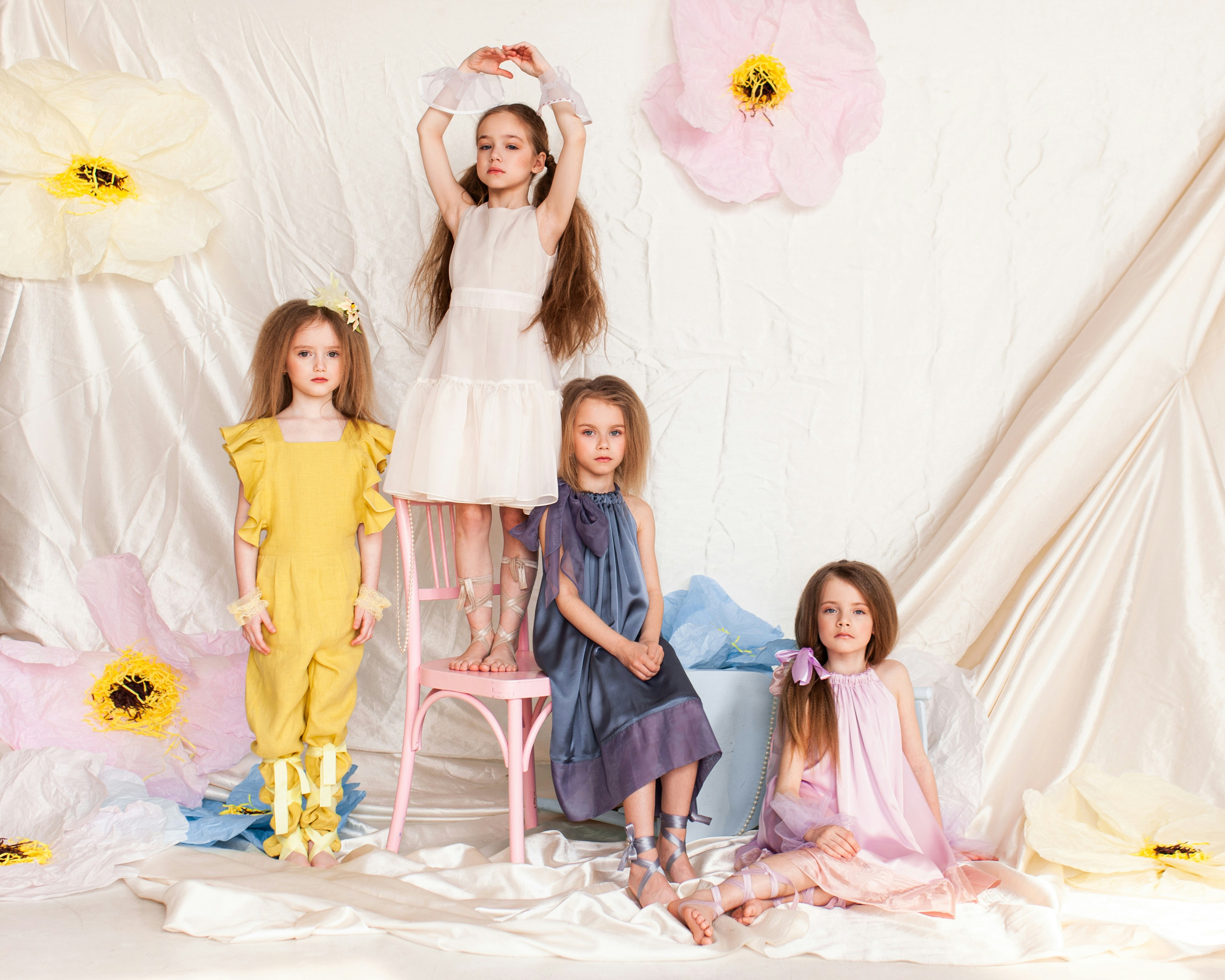白いベッドに座っている青いドレスを着た2人の女の子