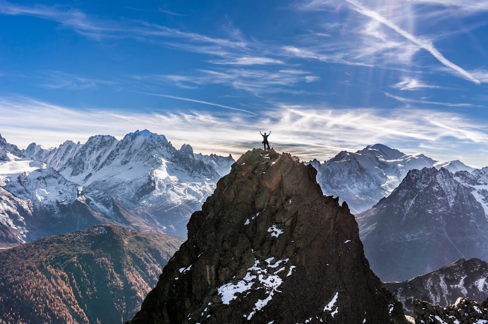 person standing on rock mountain under blue sky during daytime