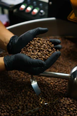 person holding coffee beans on stainless steel faucet