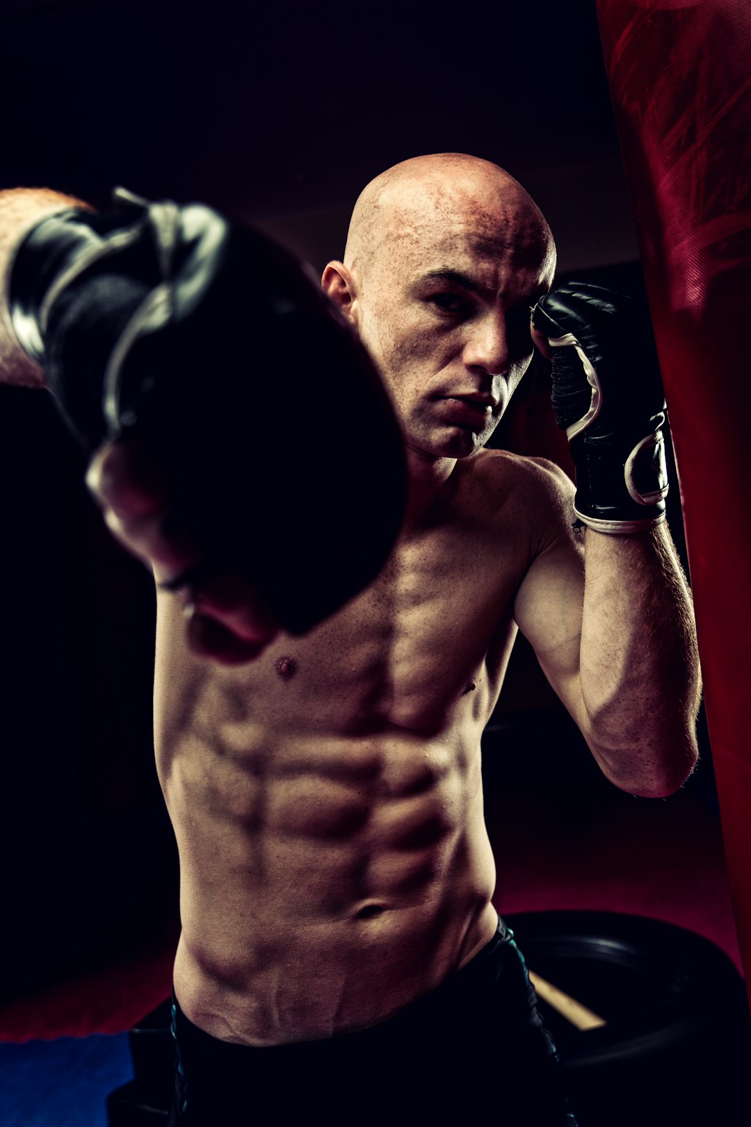 topless man in black and white shorts holding black and white boxing gloves