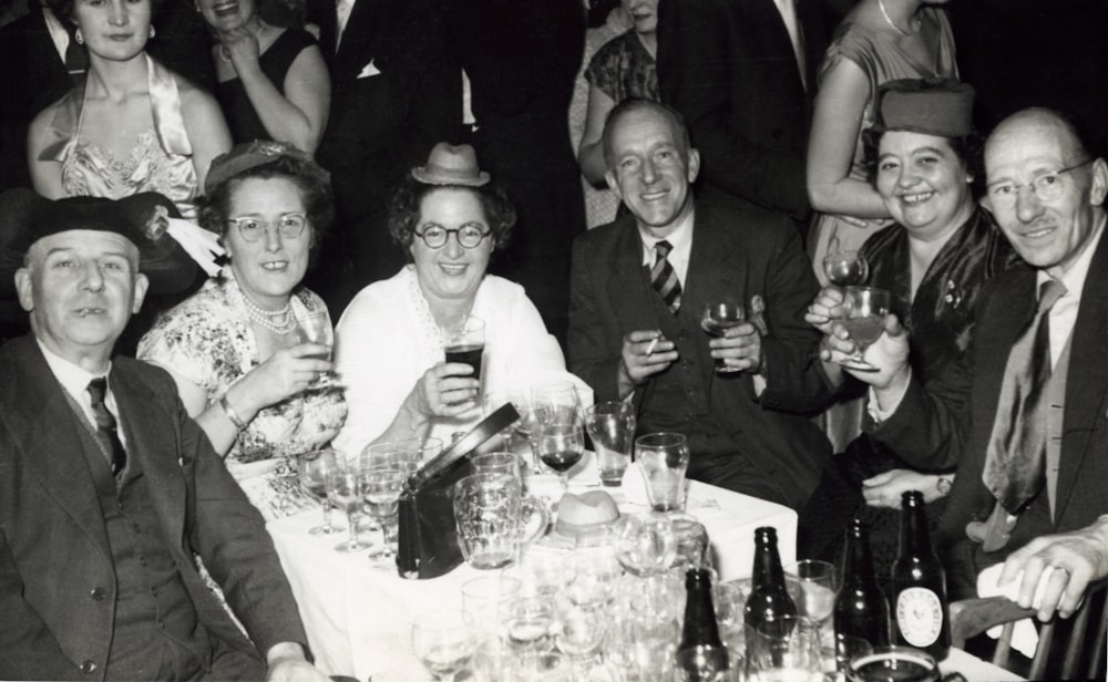grayscale photo of group of people in front of table with drinking glasses