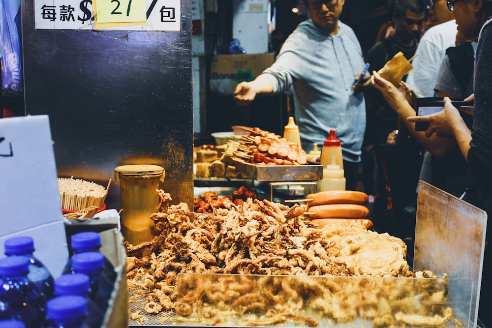 man in gray dress shirt standing near food stall