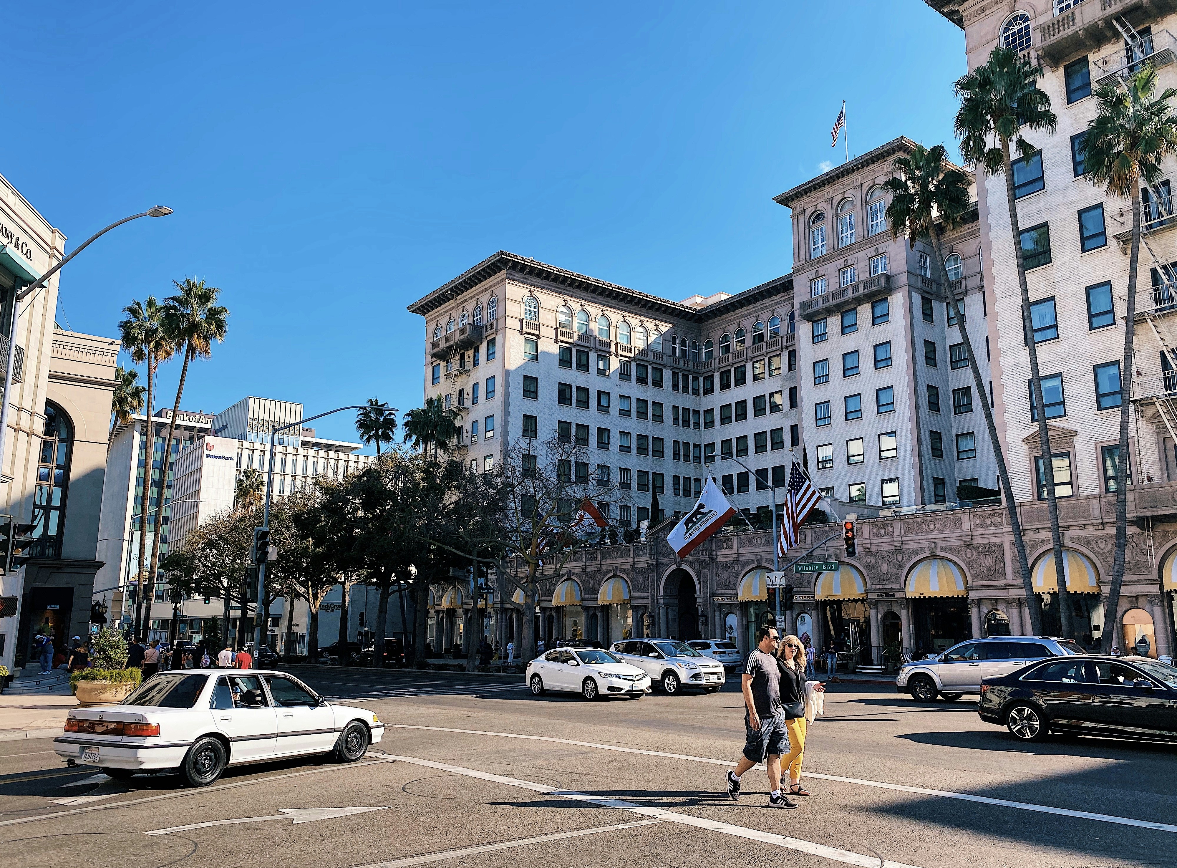 Mujer con camisa amarilla y pantalones cortos negros caminando por la acera durante el día