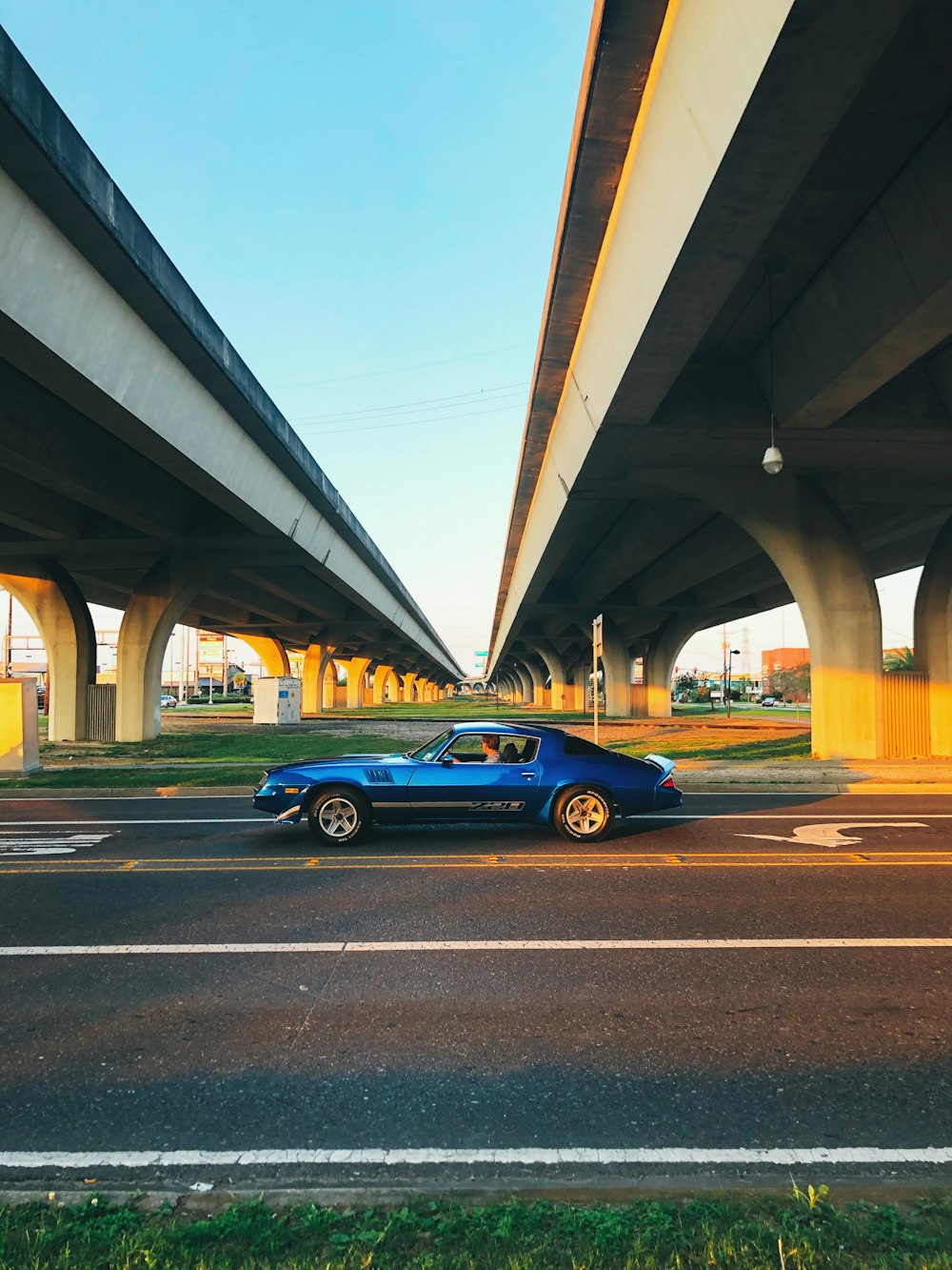 blue coupe on gray concrete bridge during daytime