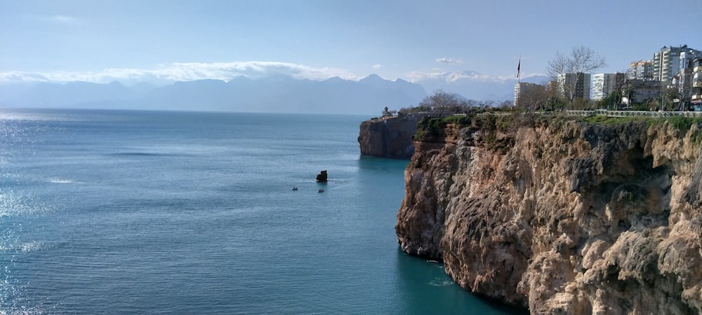 brown and green mountain beside blue sea under blue sky during daytime