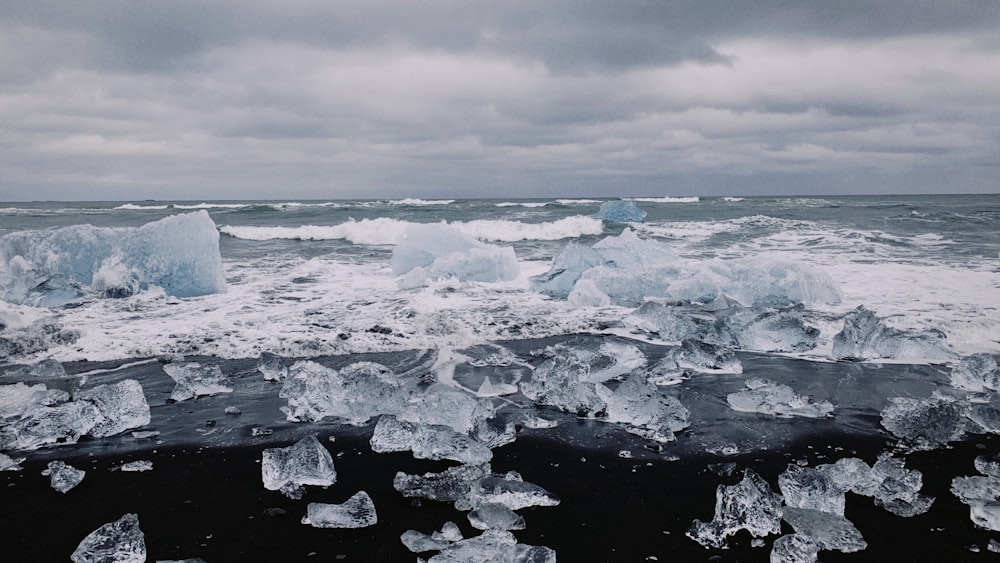 ocean waves crashing on rocks under cloudy sky during daytime