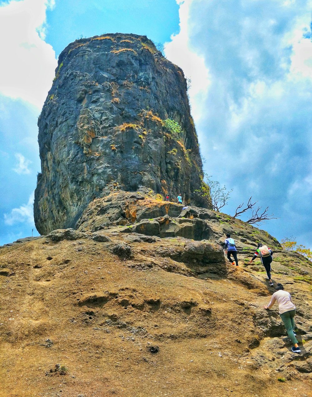 person in blue jacket and green pants climbing on rocky mountain during daytime