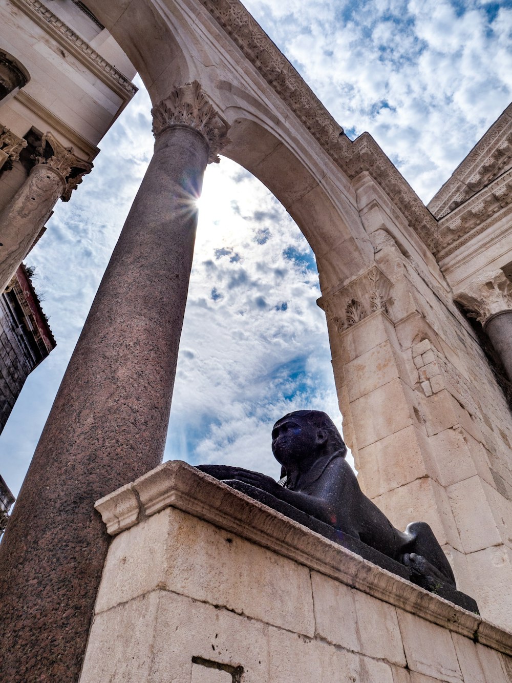 Statua dell'uomo sotto il cielo nuvoloso blu e bianco durante il giorno