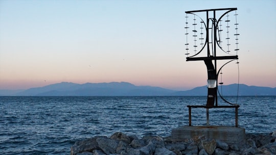 brown wooden lifeguard chair on gray rock near body of water during sunset in Kuşadası Turkey
