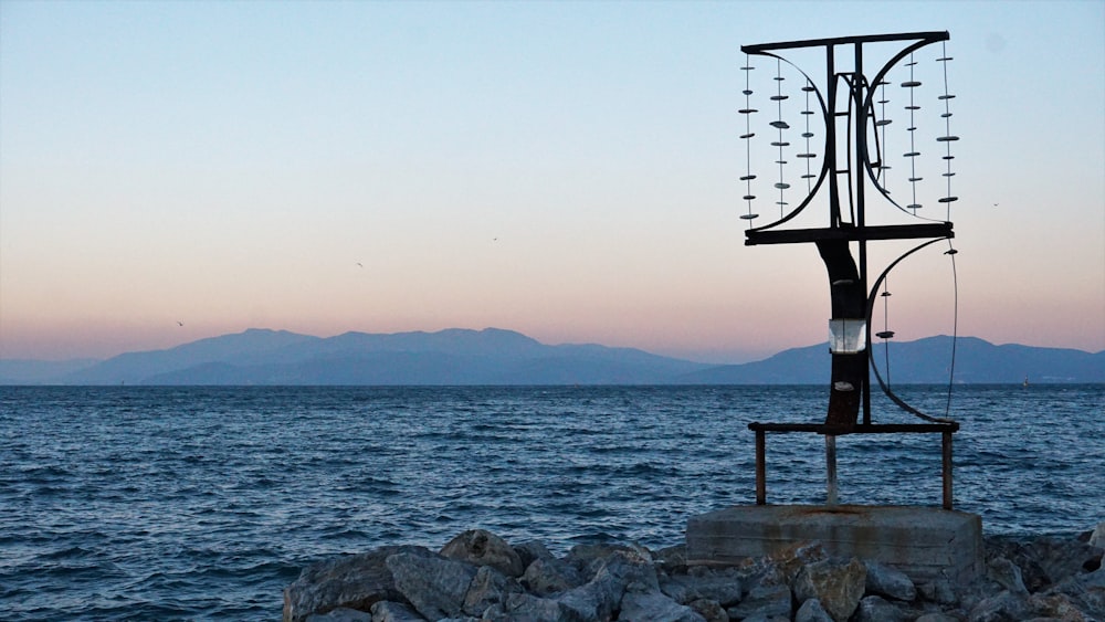 brown wooden lifeguard chair on gray rock near body of water during sunset