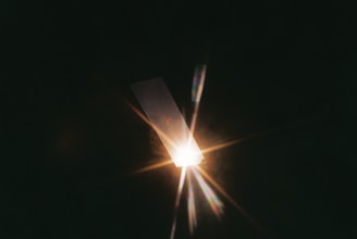 A bright light source emanating beams of light and a lens flare effect against a dark background.
