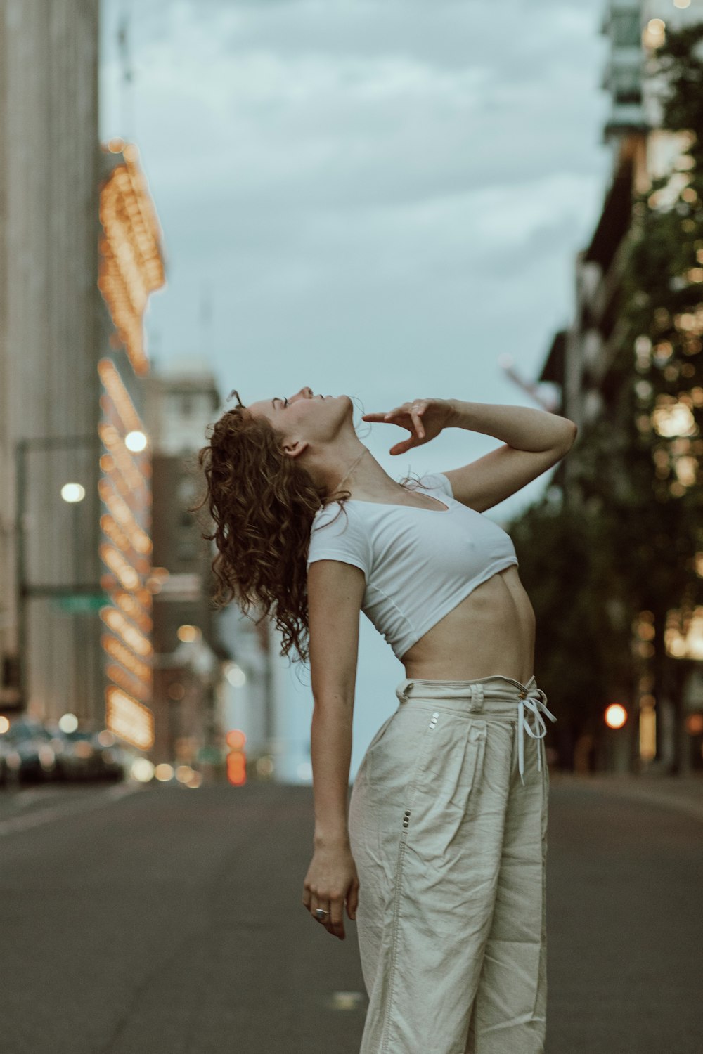 woman in white crop top and gray denim shorts raising her hands