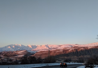 black car on road near brown mountains during daytime