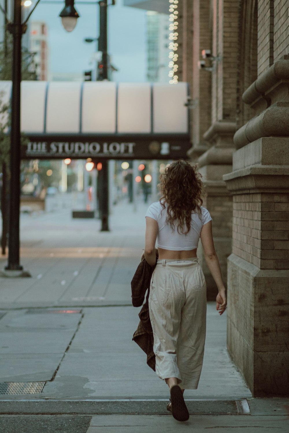 woman in white sleeveless dress standing on sidewalk during daytime